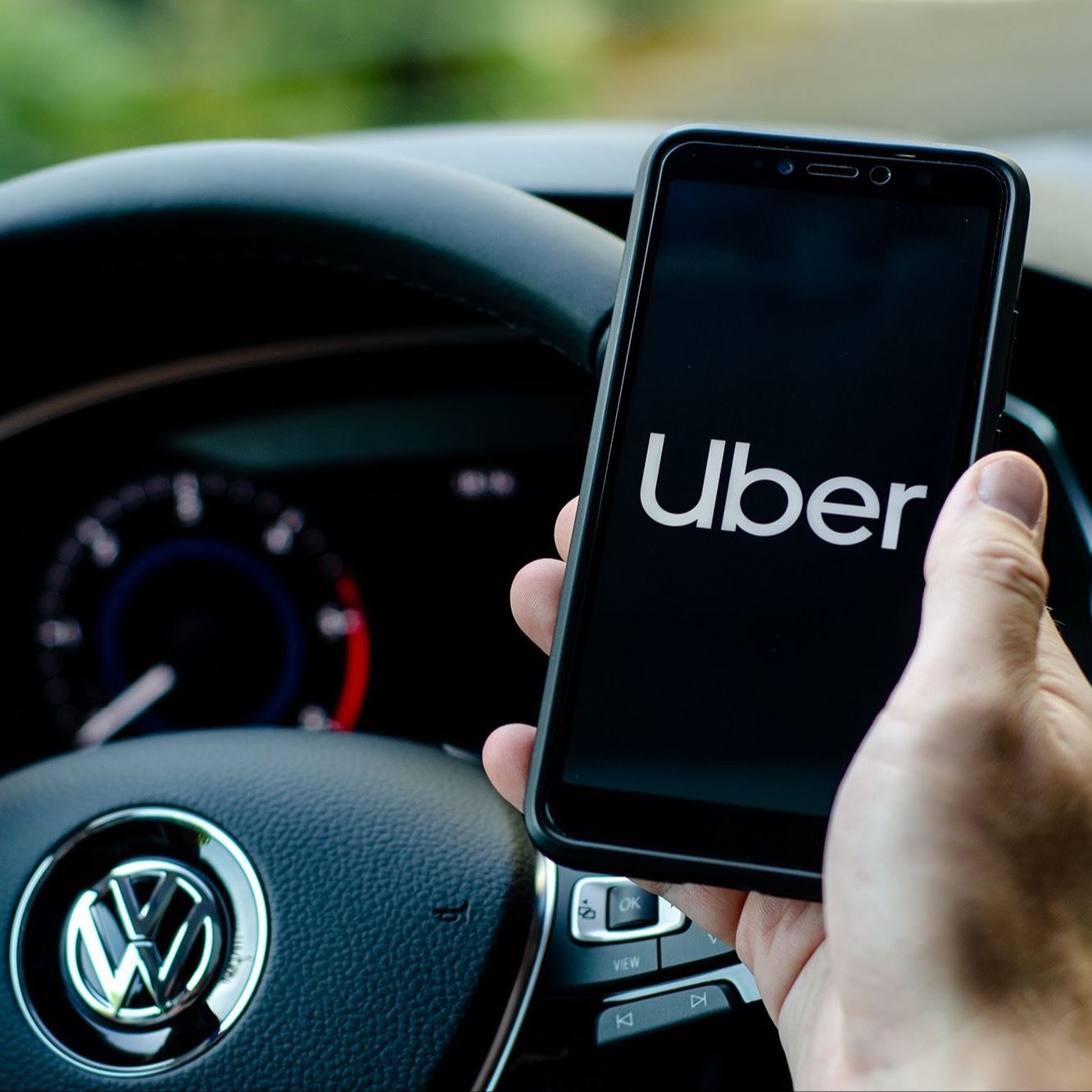 Uber driver holds cell phone with Uber app