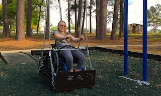 Girl in wheelchair swings at Stamper Park