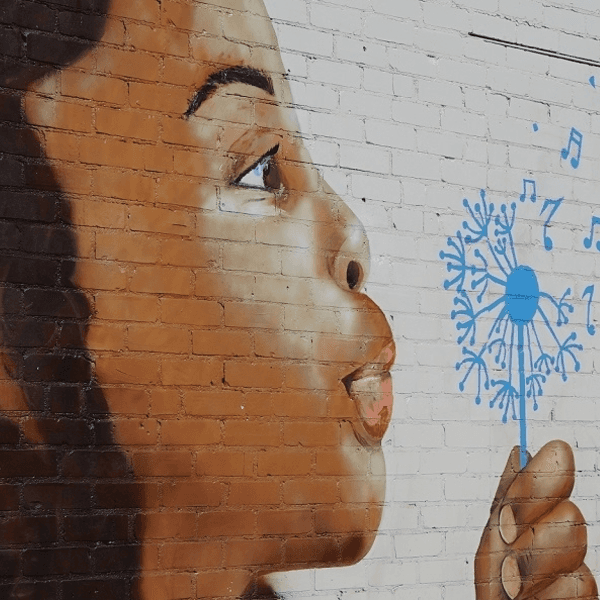 Mural of a hand holding a blue dandelion, with seeds turning into musical notes and numbers.